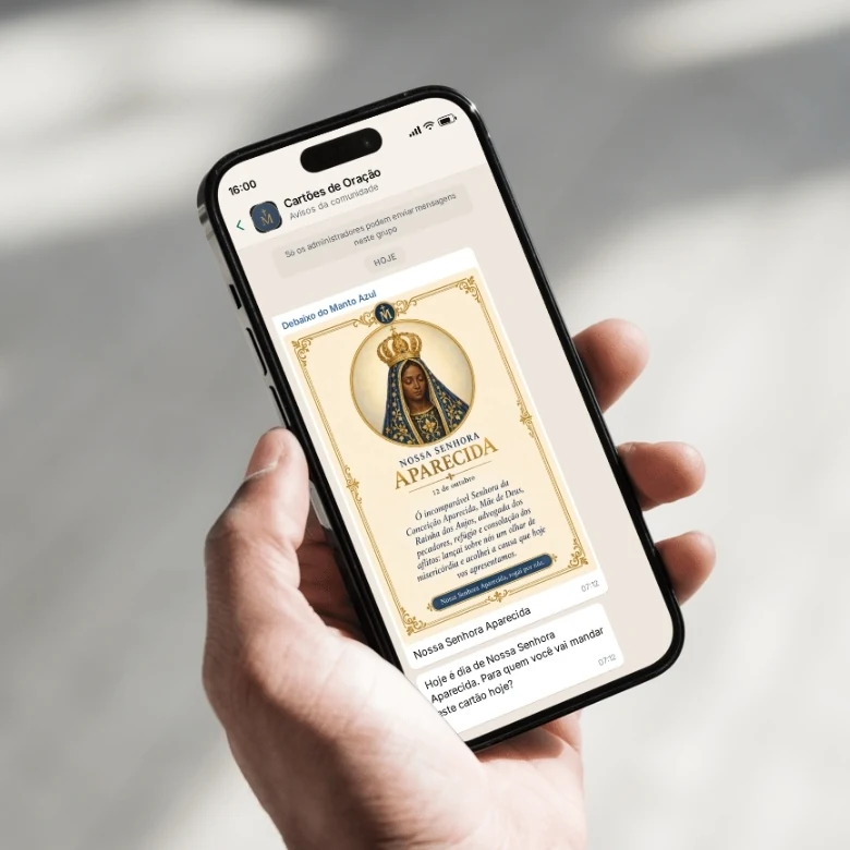 Uma mão segurando o celular com o cartão de Nossa Senhora Aparecida recebido na comunidade